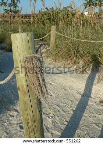 Fence post on beach path to motel in distance