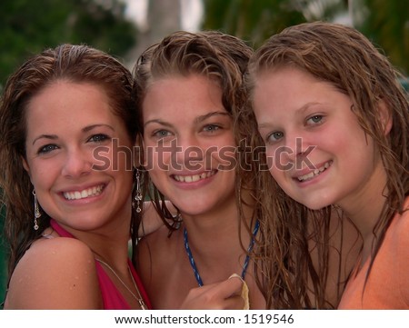Three beautiful smiling teenage girls with wet hair. All three are blue eyed blonds. Medium distance shot is from shoulders up. The girls appear to be wearing bathing suits. Good image for summer fun.