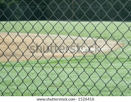 Detail of chain link fence in front of distant baseball field