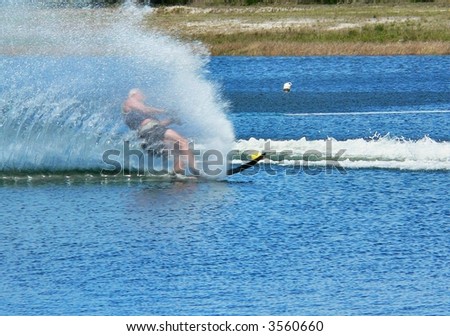 Plume of spray from passing water skier on bright blue lake or river