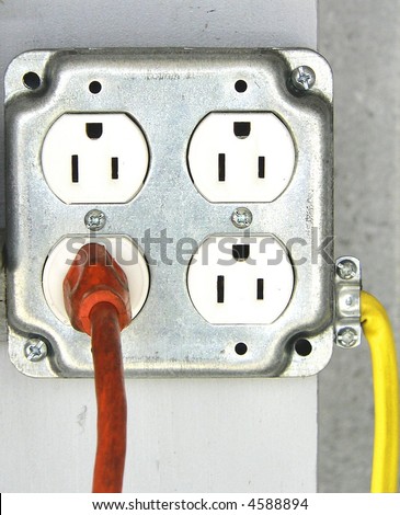 interesting detail of quad outlet with one orange cord going out and one yellow cord going in