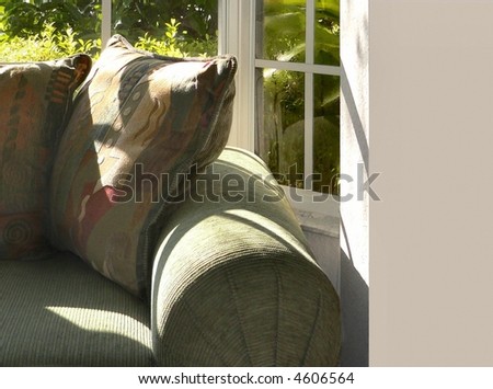 Inviting corner of a soft green couch with sun streaming in from window