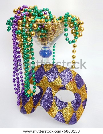 Purple, green and gold mardis gras, or Fat Tuesday, beads overflow a large martini glass with a purple and gold harlequin mask leaning again the glass. Vertical image for party background