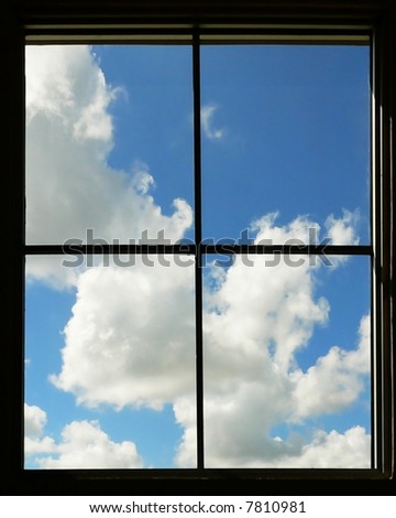 Puffy white clouds and blue sky framed in a 4 pane window. The window trim is painted black. There is sun shining on the right side of the window. Vertical composition. One pane has almost no clouds.