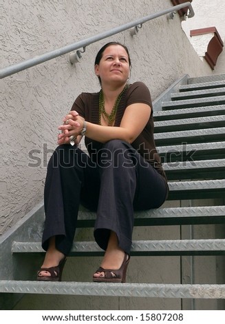 Attractive brunette woman looking deep in thought while sitting on steps
