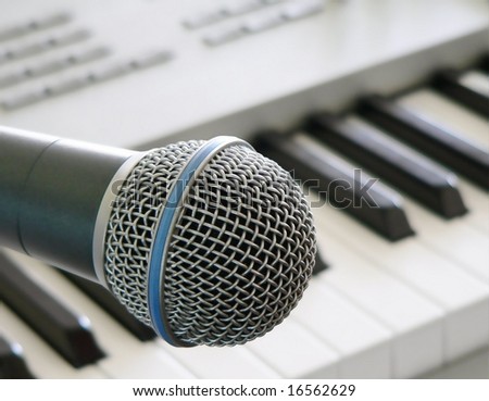 close up of vocal microphone with blurred electronic keyboard in distance