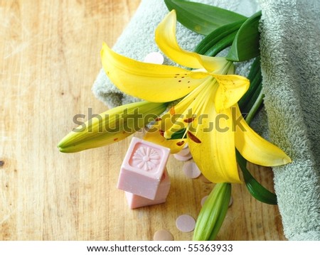 Spa style still life of bright yellow lily with designer soaps and a soft green towel