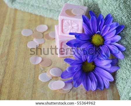 Spa still life with decorative soaps, soap flakes, blue daisies and a soft green towel