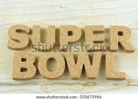 NFL football theme with block letters made out of cork on a wooden background. Letters spell Super Bowl. Lots of texture and neutral colors in the horizontal image.