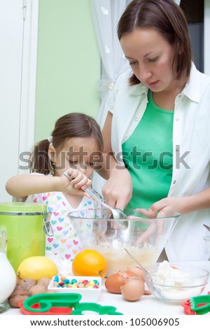 daughter helping her mother to bake a cake