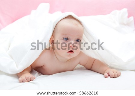 Baby girl with blue eyes under a white blanket.