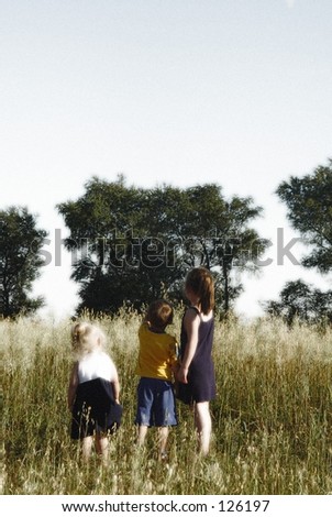 Soft focus three children in misty field.  Room for copy.