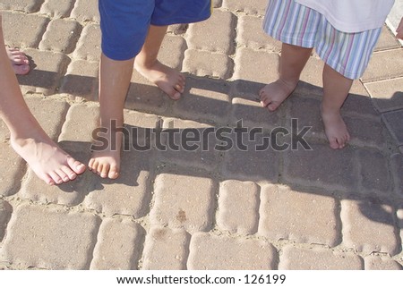 Three little children stepping on each others  shadows