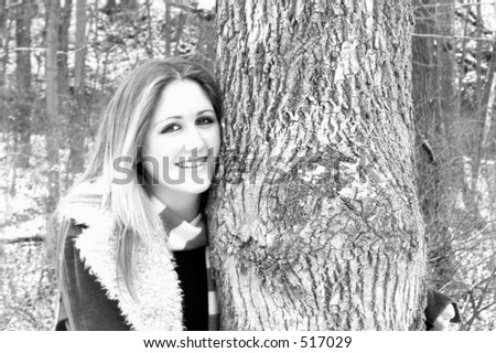 Pale teenage girl in wool lined coat posing with tree. Dental appliance evident. Black and white