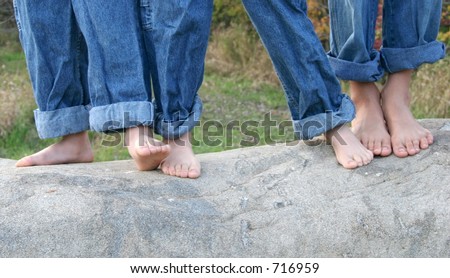 Three brothers dancing barefoot on rock.