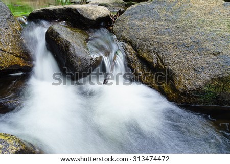 Rocks with waterfall in the forest with the recording . To get the waterfall with soft comfortable hand firmly on the hardness of the rocks make it look just a stone . Water alone
