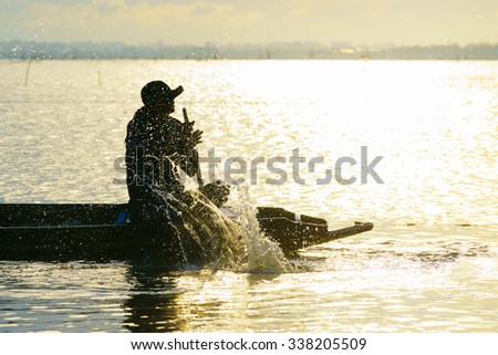 Silhouette image of fisherman in the morning work at the Songkhla Lake,Songkhla Thailand.Selective focus with shallow depth field.
