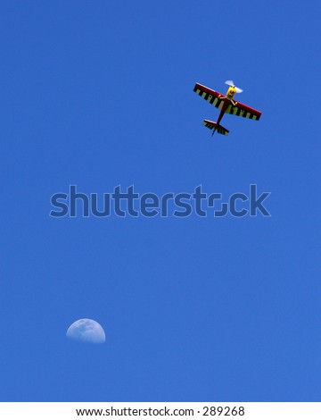 Radio-controlled airplane against blue sky with moon backdrop