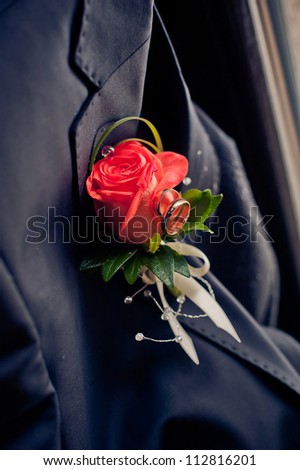 red rose wedding boutonniere on suit of groom. wedding rings