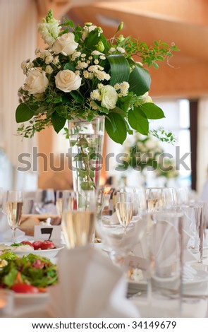 Table setting for a wedding or dinner event, with flowers in vase of glass