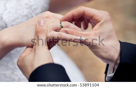 Groom putting a ring on bride\'s finger during wedding ceremony
