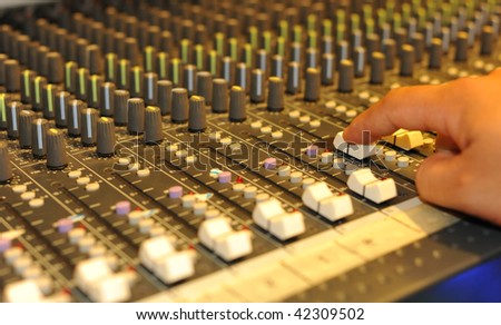 Close-up of sound engineer\'s hand moving sliders on audio mixing board