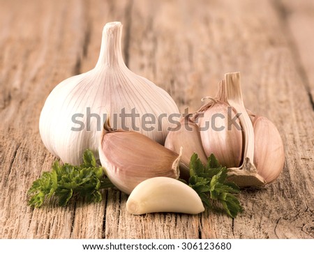 Garlic with parsley on a wooden background.