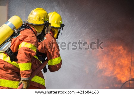 2 firefighters spraying water fire fighting operation