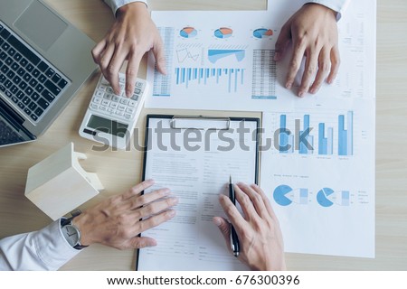 Man sign a home insurance policy on home loans, Agent holds loan investment chart graph documents and calculating table installment payment, Real Estate concept.