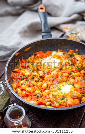 Shakshuka Breakfast of Fried Eggs, Tomatoes, Paprika, Red Hot Chili Pepper and Herbs in a Pan, Vertical View From Above