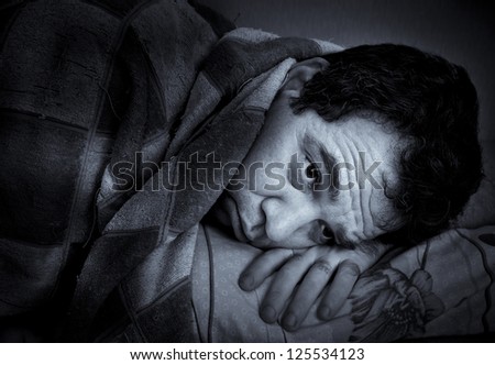 Insomnia. A man tries to fall asleep. Blue tinted