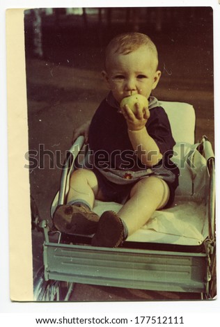 KURSK, USSR - CIRCA 1970: An antique photo shows portrait of a little boy eating an Apple sitting in a wheelchair.