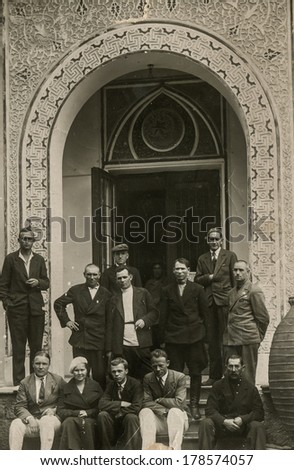 FERGANA, UZBEKISTAN, USSR - CIRCA 1930s: An antique photo shows group of Russian tourists standing near the ancient palace. \