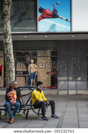 STUTTGART, GERMANY - APRIL 01, 2014: Old man and young man sitting on a bench resting on  main street of city - KÃ?Â¶nigsstrasse