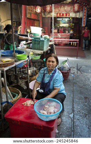 BANGKOK, THAILAND - DECEMBER 25, 2014: Street Photography of Street market in China town.  A woman prepares a dish of chicken.