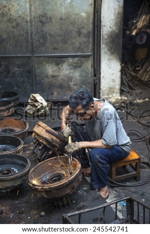 BANGKOK, THAILAND - DECEMBER 25, 2014: Street Photography of  auto  mechanic repairs old rims.