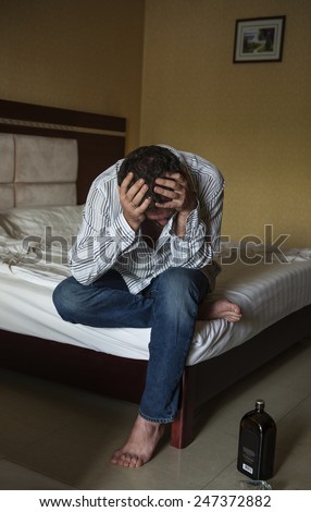 Man sitting on the bed with headache depression and hangover.