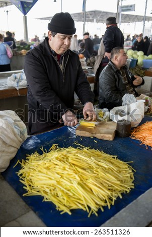 SAMARQUAND, UZBEKISTAN - MARCH 14, 2015: City grocery market. Man sells yellow carrots for Uzbek national dish - plov.