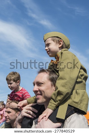 MOSCOW - MAY 9, 2014: Victory day celebrations in Moscow. Boy in military form sits on shoulders of his father.