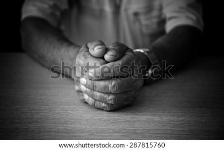 Wrinkled hands elderly man at table. Black and white photo