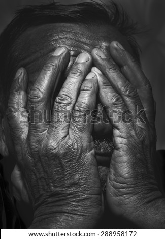 portrait of senior man covering his face with his hands. black and white image