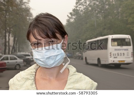 Smog in the city. A woman in medical mask