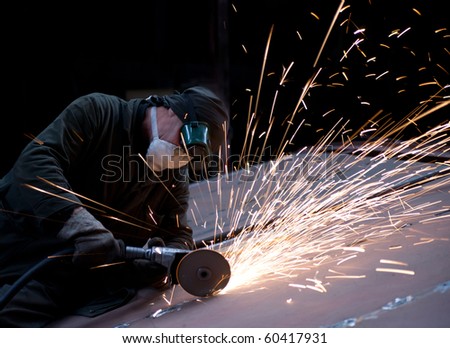Worker cutting metal using rotary disc