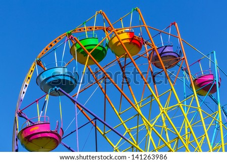 Scenic summer view of color Ferris observation wheel over blue sky in amusement park