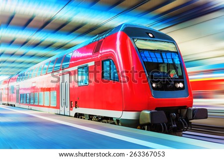 Railroad travel and railway tourism transportation industrial concept: scenic view of red modern high speed passenger commuter double decker train on tracks at the station platform with motion blur