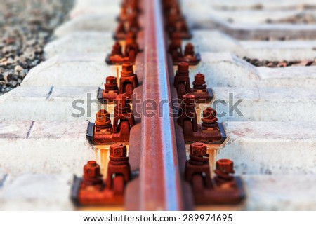 Creative abstract railway transportation industry and railroad cargo shipping business infrastructure industrial concept: macro view of metal train rail and sleepers with selective focus effect