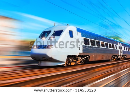 Railroad travel and railway tourism transportation industrial concept: scenic summer view of modern high speed passenger commuter train on tracks at the station platform with motion blur effect