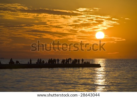 People who go and listen to music on the pier in Trieste Audace with the sunset in the background
