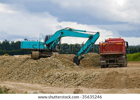Excavator loading sand or rocks in lorry