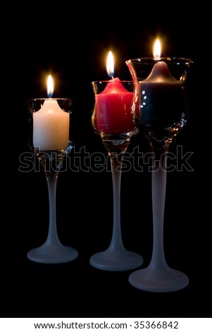 Three (3) Candles burning in decorative candle holders.